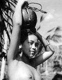 A young Balinese girl posing with a water pot balanced on her head, c.1945.